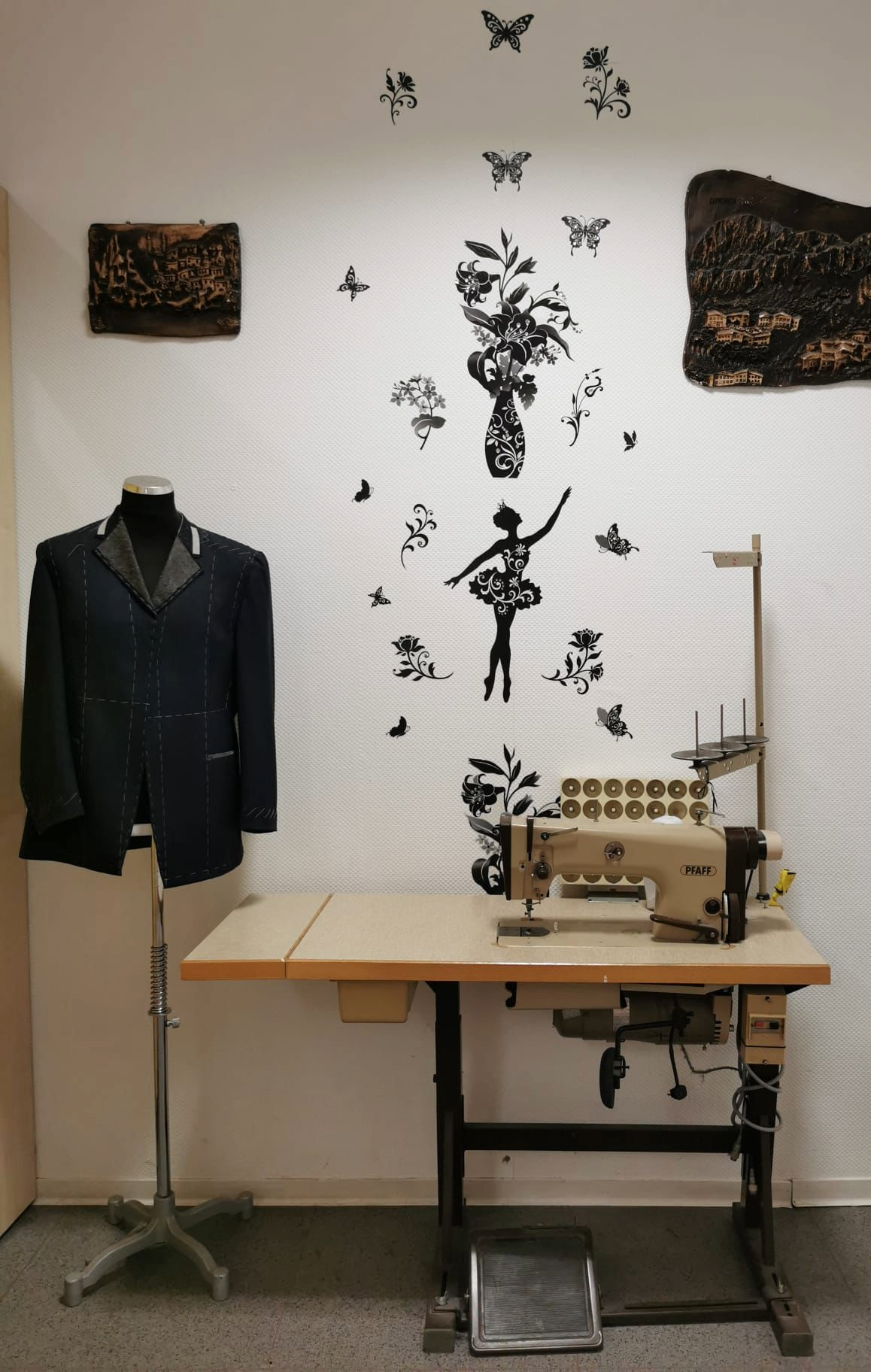 Eindruck aus der Schneiderei: Sakko an einer Schneiderpuppe neben einer industriellen Pfaff-Nähmaschine